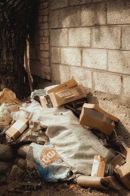 The image depicts two large industrial blue containers filled with discarded used black tires, piled haphazardly and occupying most of the space within each container. The tires, made of rubber with v